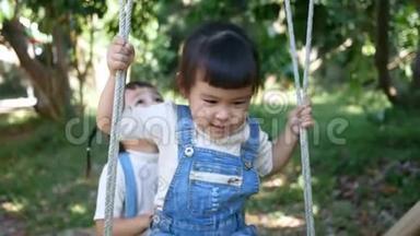 可爱快乐的小女孩喜欢和姐姐在后院玩竹秋千。